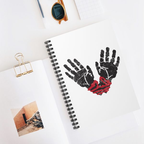 spiral notebook with the symbol of ilmater, hands bound with a red cord, on desk