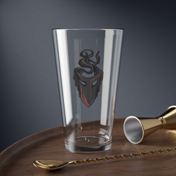 16 oz pint glass with the dnd symbol of Mask, fantasy deity of dungeons and dragons rogues and thieves, on desk