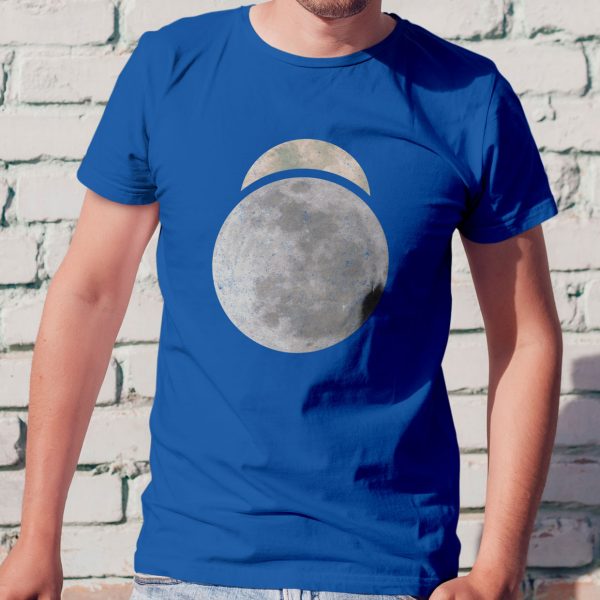 The symbol of Sehanine Moonbow, a misty crescent above a full moon, on a royal blue shirt standing against a wall
