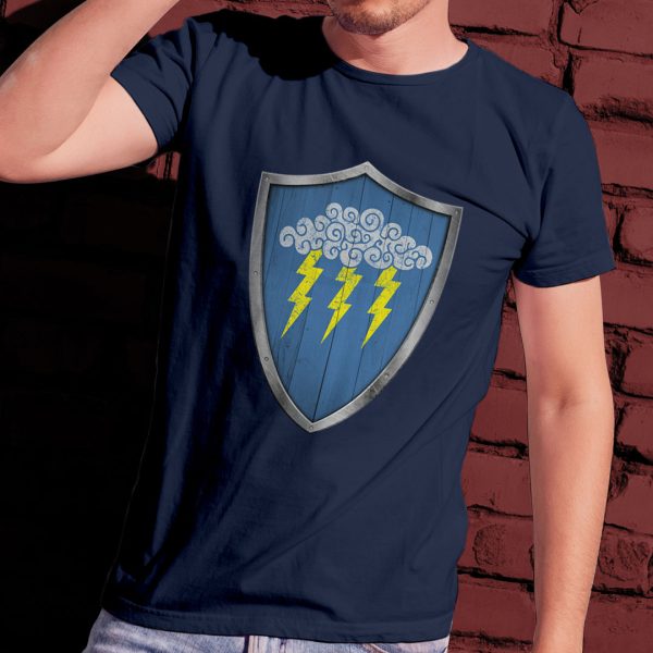The DnD symbol of Valkur, a cloud with three lightning bolts on a shield, on a navy blue shirt worn by a man leaning against a brick wall