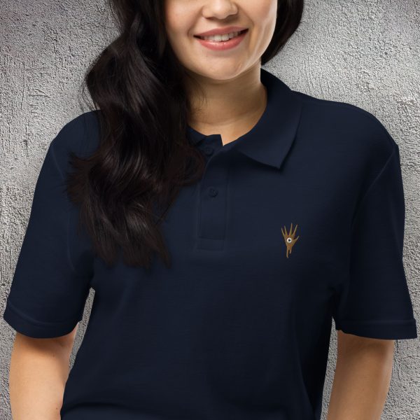 A shirt with the symbol of Vecna, a hand with an eye in the palm, the undead lich well-known in DnD, on a navy blue shirt worn by a woman up close