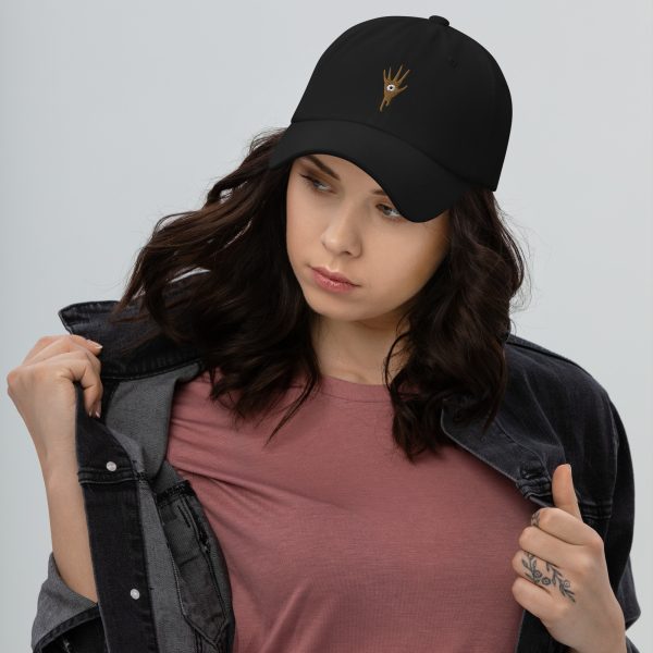 A black DnD hat with the symbol of Vecna, evil lich and villain, worn by a woman, casual