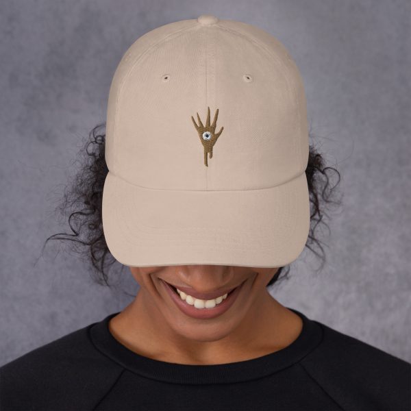 A sand DnD hat with the symbol of Vecna, evil lich and villain, on woman looking down