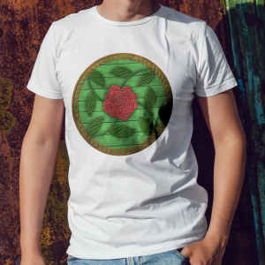 The symbol of Chauntea on a shield, a blooming rose on a sunburst wreath of golden grain. Chauntea is the goddess of life and agriculture. On a white shirt worn by a man against a wall.