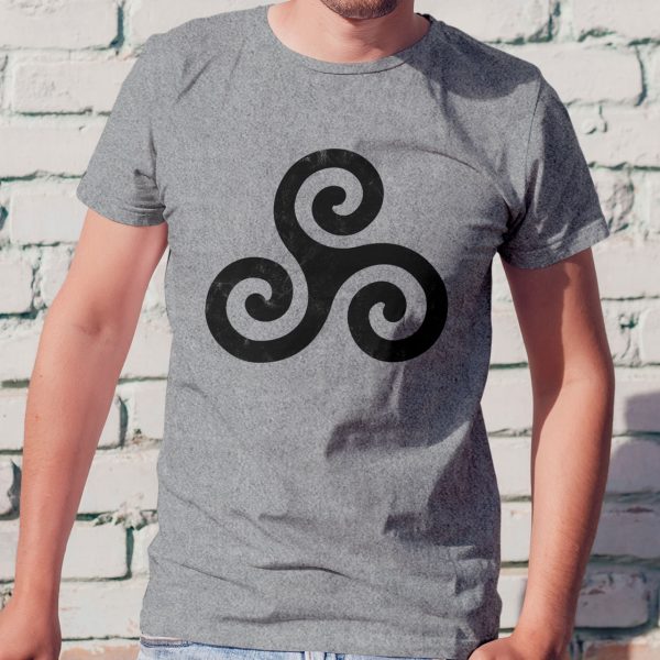 A sport gray shirt with the symbol of Trithereon. His symbol, the Rune of Pursuit, illustrates the need to fight for freedom and to put an end to the actions of those who seek to restrict it. Worn by a man against a wall.