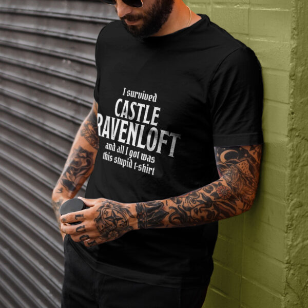 A black D&D shirt telling people that you survived castle ravenloft of the Curse of Strahd, worn by a man leaning against a wall