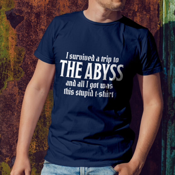 A navy blue D&D shirt telling people that you survived the Abyss, a demonic realm in D&D, worn by a man against a wall