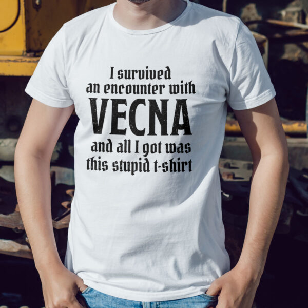 A white D&D shirt telling people that you survived a D&D encounter with the powerful lich Vecna, worn by a man against a wall